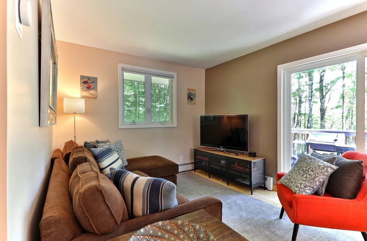 A comfortable living space featuring a sofa facing a television, with a window view letting in natural light. The room is set up for relaxation and socializing, inviting guests to gather for a casual evening indoors after a night out.