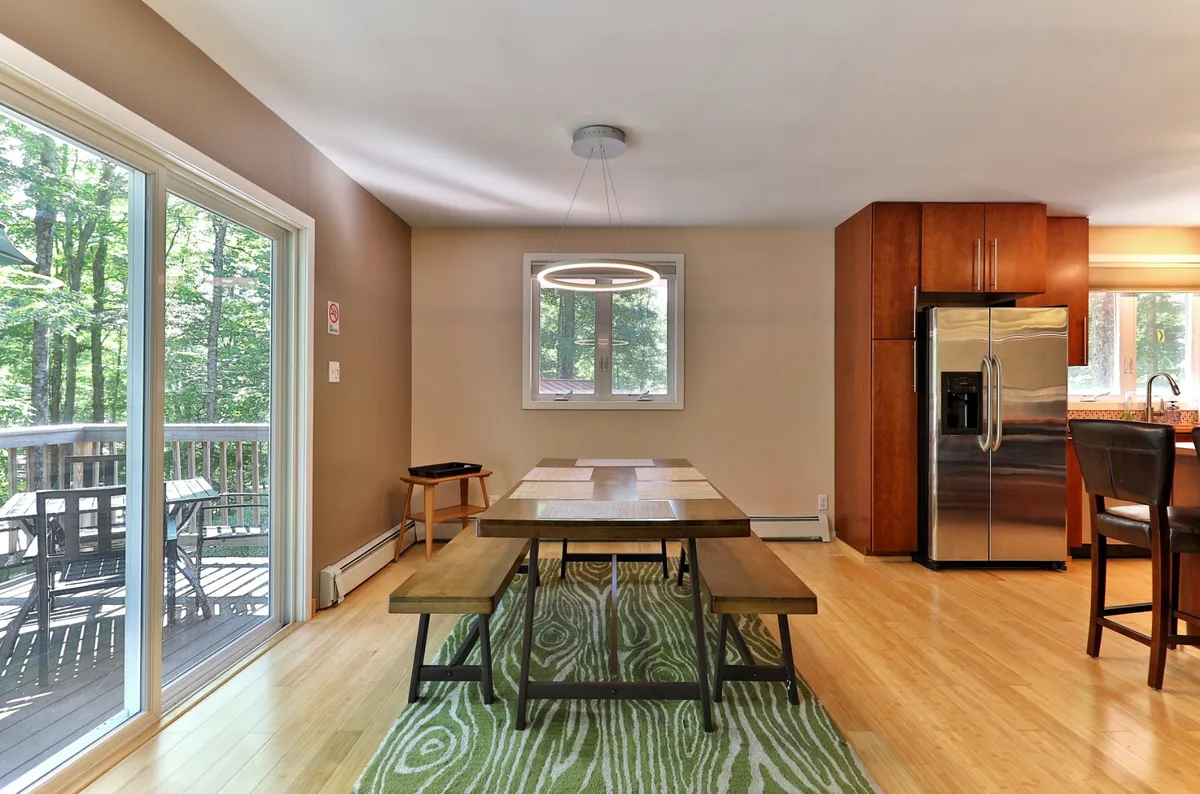 A cozy dining table set beside a large window with plenty of natural light, adjacent to kitchen appliances and cabinetry. The setting suggests an inviting spot for family meals or morning coffee.
